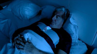 men sleeping in his bed with a smartphone taped to his chest