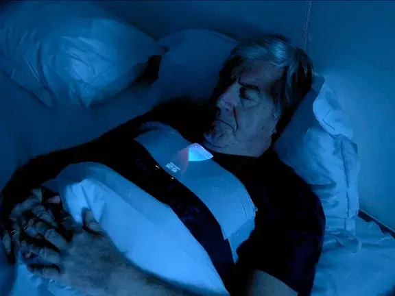 men sleeping in his bed with a smartphone taped to his chest